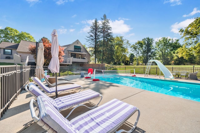 view of pool with a water slide and a patio area