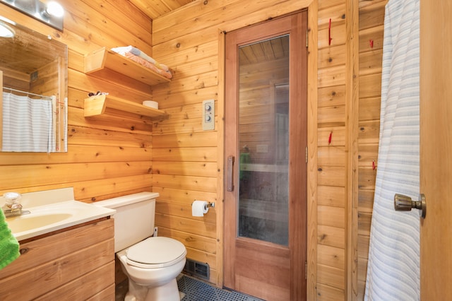 bathroom with wooden walls, toilet, and vanity