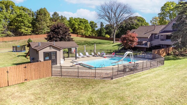 view of pool featuring a diving board, a lawn, a water slide, and a patio area