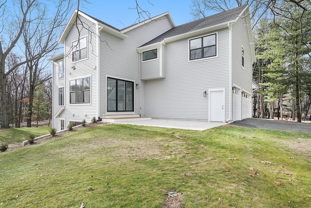 rear view of property with a yard, a garage, and a patio