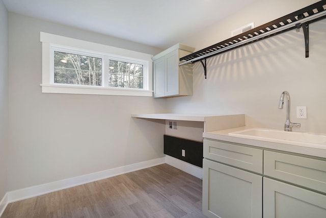 laundry area with cabinets, sink, and light wood-type flooring