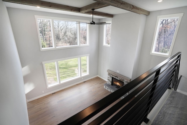 stairway featuring beam ceiling, a stone fireplace, and wood-type flooring