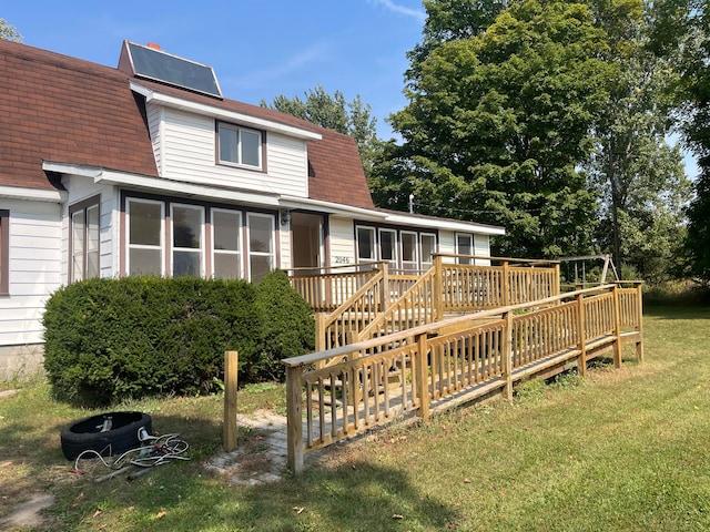 rear view of house with a yard, a sunroom, and a deck