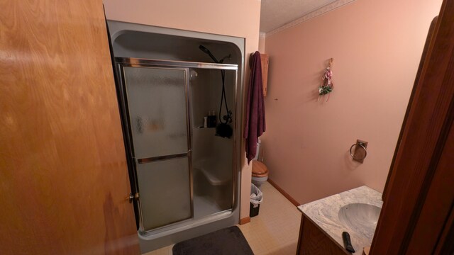 bathroom featuring a shower with door, vanity, toilet, and ornamental molding