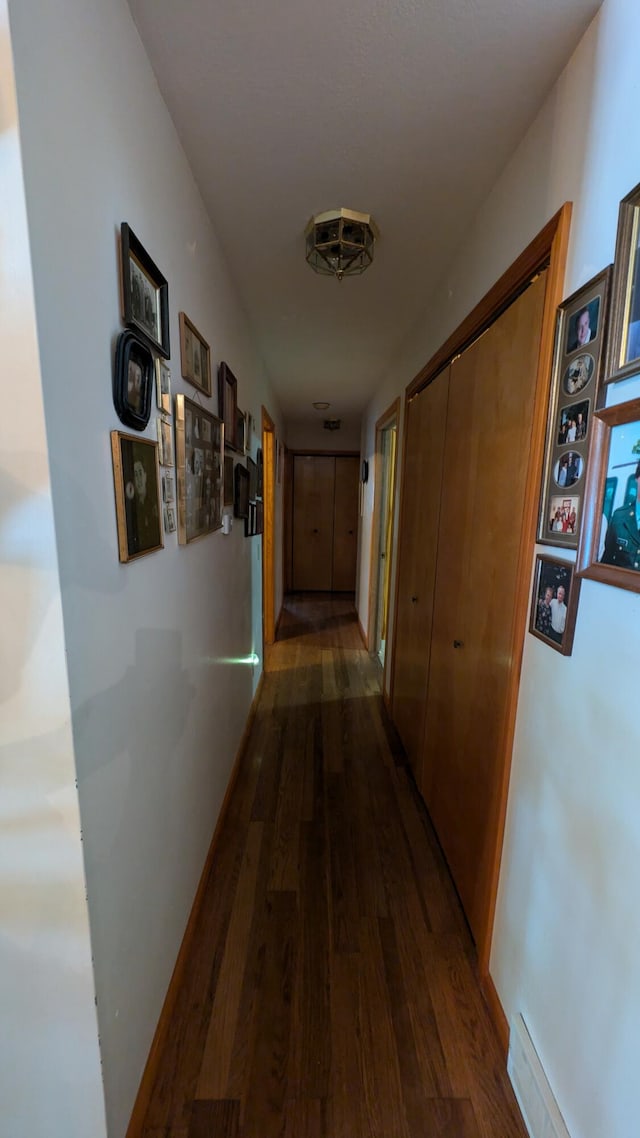 hall with a baseboard heating unit and dark hardwood / wood-style flooring