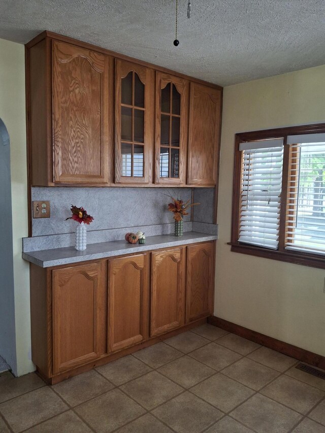 kitchen featuring a textured ceiling, decorative backsplash, and light tile patterned flooring