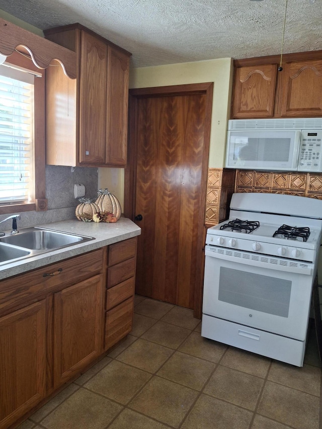 kitchen with tile patterned flooring, a textured ceiling, sink, decorative backsplash, and white appliances