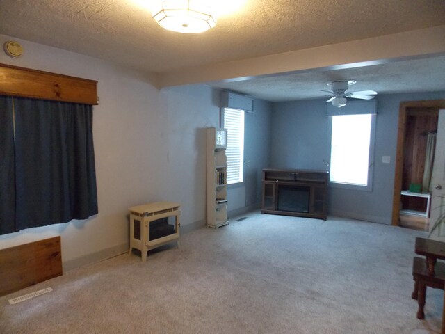 carpeted living room featuring a textured ceiling and ceiling fan