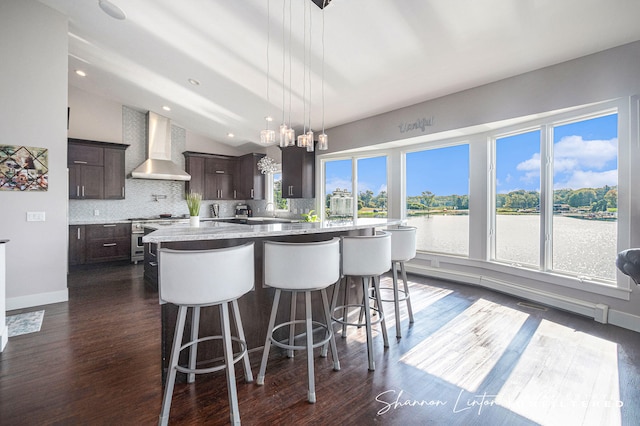 kitchen with vaulted ceiling, dark brown cabinetry, tasteful backsplash, a large island, and wall chimney range hood