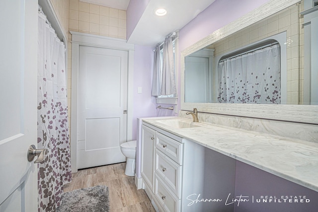 bathroom with recessed lighting, wood finished floors, toilet, and vanity