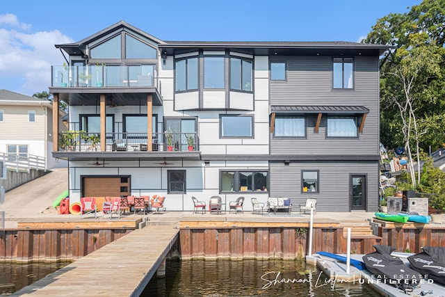 back of property with a balcony and a water view