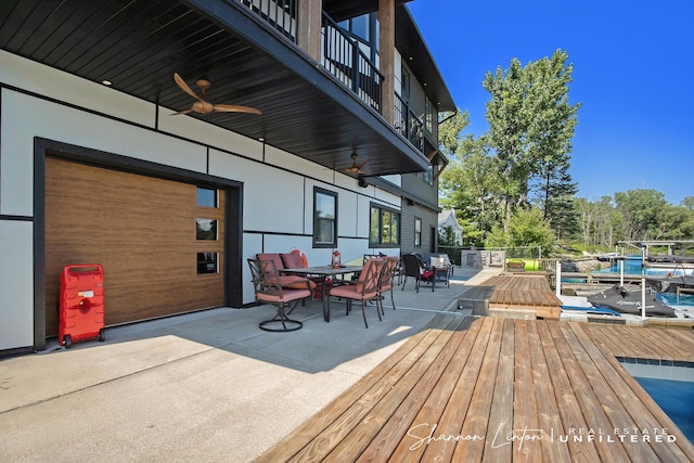 deck featuring outdoor dining space, a ceiling fan, and a dock