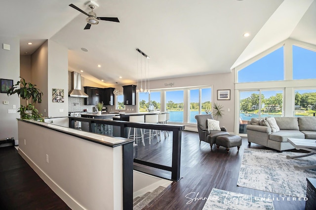 interior space with dark wood-type flooring, high vaulted ceiling, wall chimney range hood, and a ceiling fan