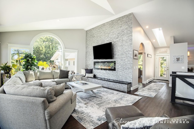 living area featuring arched walkways, dark wood-style flooring, a fireplace, and plenty of natural light
