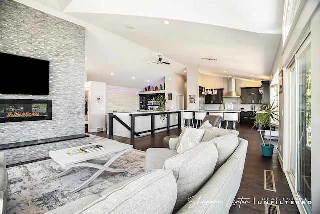 living room with vaulted ceiling, a fireplace, dark wood finished floors, visible vents, and ceiling fan
