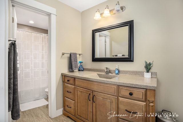 bathroom with a shower with shower curtain, wood finished floors, toilet, and vanity