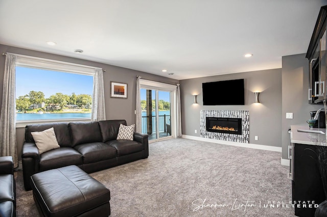 living area featuring baseboards, carpet floors, a glass covered fireplace, and recessed lighting