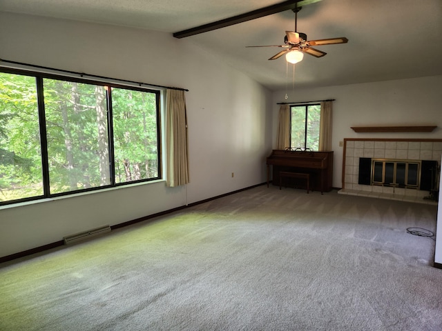 unfurnished living room featuring ceiling fan, light carpet, a tile fireplace, and lofted ceiling with beams