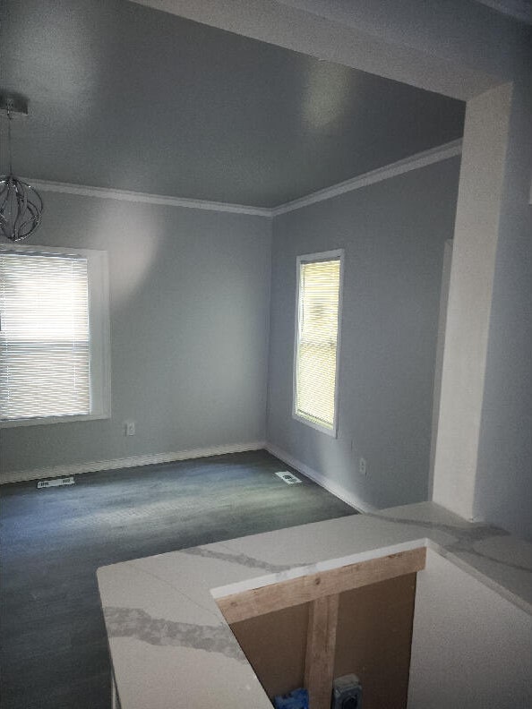 empty room with ornamental molding and a chandelier