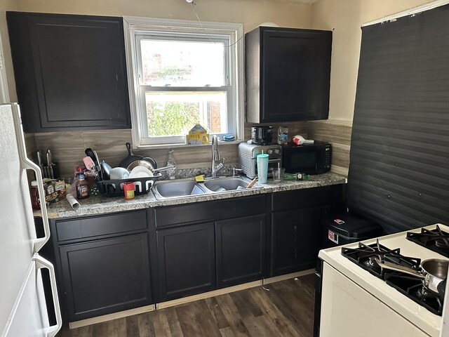 kitchen featuring white appliances, dark hardwood / wood-style flooring, and sink