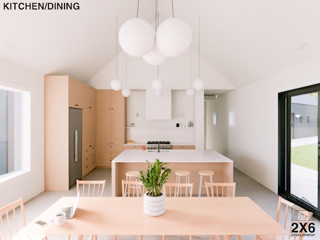 kitchen with pendant lighting, stainless steel refrigerator, sink, and high vaulted ceiling