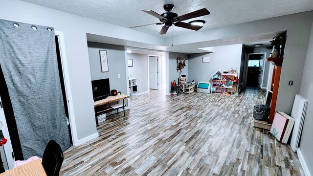 interior space featuring light hardwood / wood-style flooring, a textured ceiling, and ceiling fan