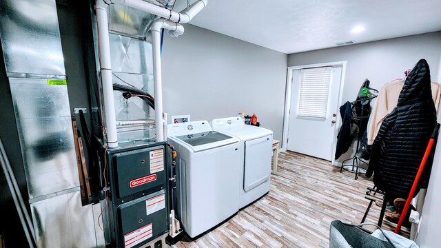 laundry area with light hardwood / wood-style flooring and washing machine and clothes dryer