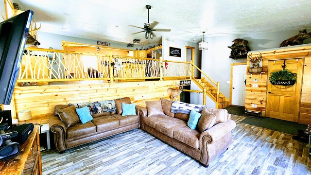 living room with ceiling fan, a textured ceiling, and wood-type flooring