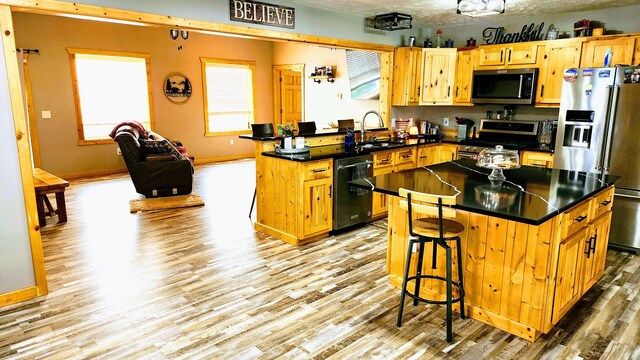 kitchen with light hardwood / wood-style floors, a center island, and stainless steel appliances