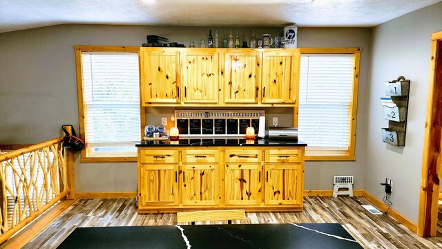 kitchen with lofted ceiling, light hardwood / wood-style floors, and a textured ceiling