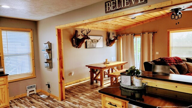 living room featuring light hardwood / wood-style flooring, vaulted ceiling with beams, a textured ceiling, and ceiling fan