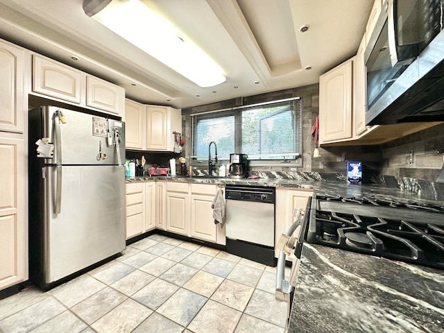 kitchen featuring decorative backsplash, stainless steel appliances, sink, and dark stone counters