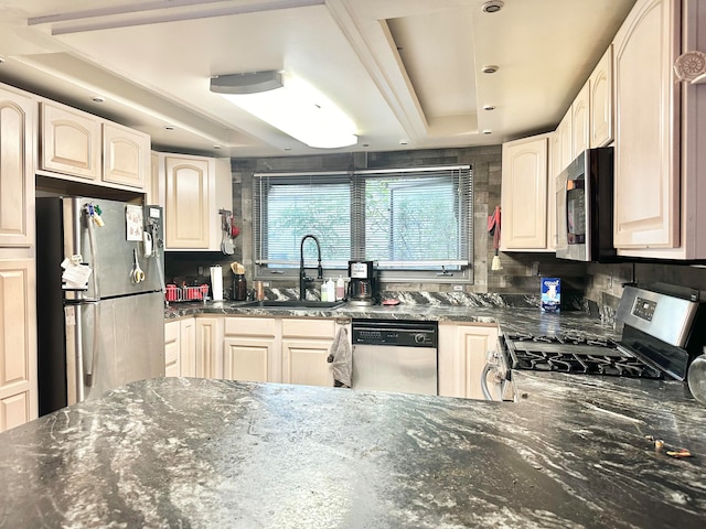 kitchen with dark stone counters, decorative backsplash, sink, and stainless steel appliances