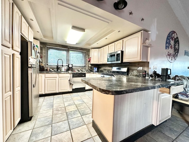 kitchen featuring a tray ceiling, sink, kitchen peninsula, backsplash, and appliances with stainless steel finishes