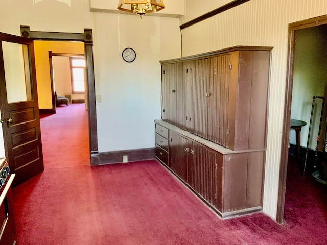 hallway with dark colored carpet and beam ceiling