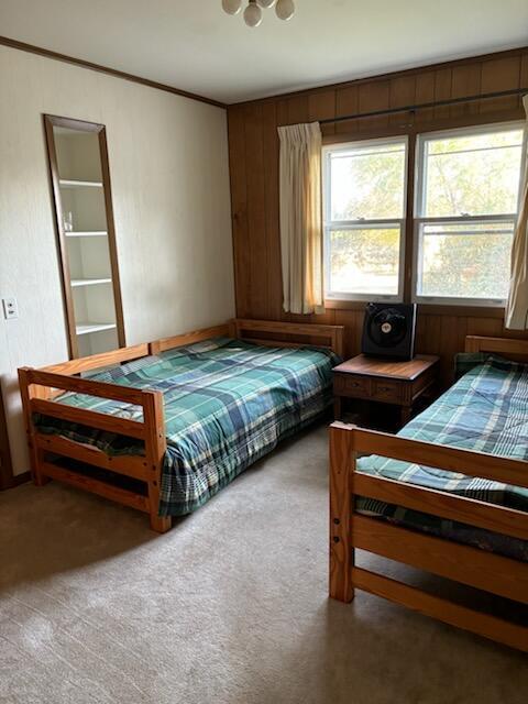 bedroom with carpet floors and wood walls