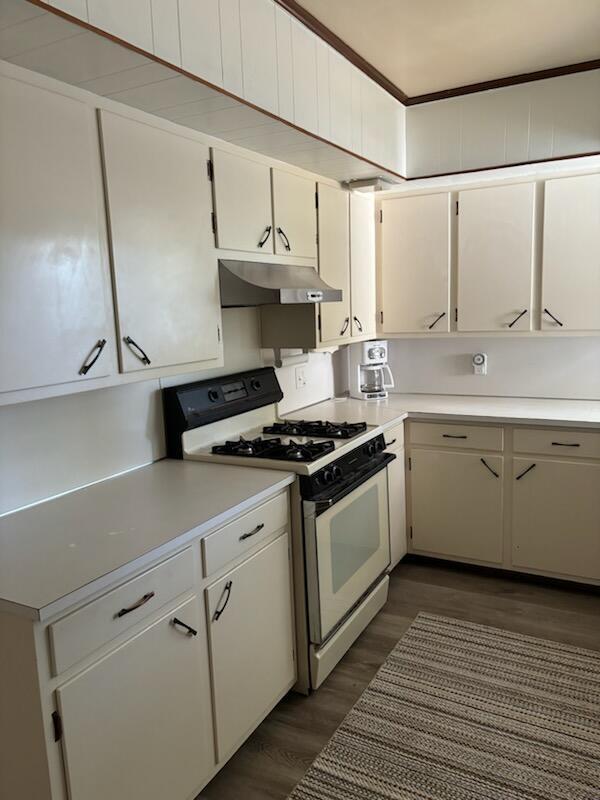 kitchen featuring dark wood-type flooring, white cabinetry, crown molding, and white range with gas cooktop