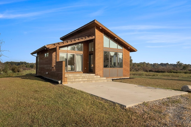 back of house with a lawn and a patio