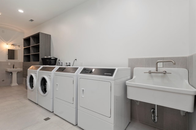 washroom featuring sink, tile walls, and washer and dryer