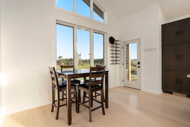 dining space featuring light hardwood / wood-style flooring and high vaulted ceiling