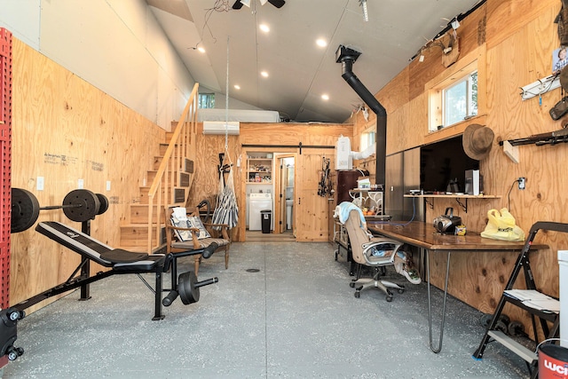 office space featuring wooden walls, a barn door, and high vaulted ceiling