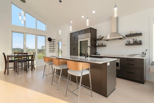 kitchen featuring appliances with stainless steel finishes, light stone countertops, decorative light fixtures, sink, and extractor fan