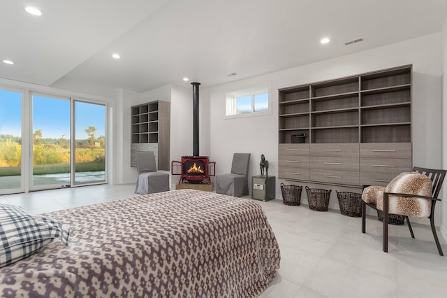 bedroom with multiple windows, a wood stove, and access to exterior