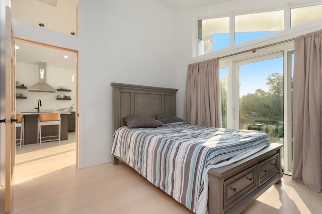 bedroom with sink, light hardwood / wood-style flooring, and a high ceiling