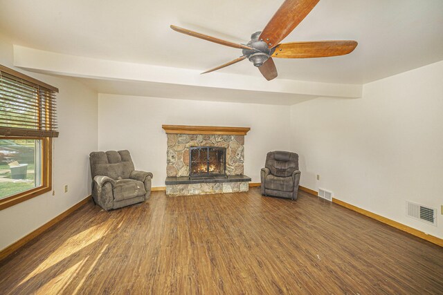 unfurnished room featuring ceiling fan, a stone fireplace, and wood-type flooring