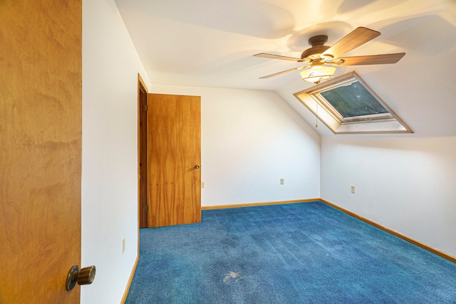 additional living space featuring lofted ceiling with skylight, dark carpet, and ceiling fan