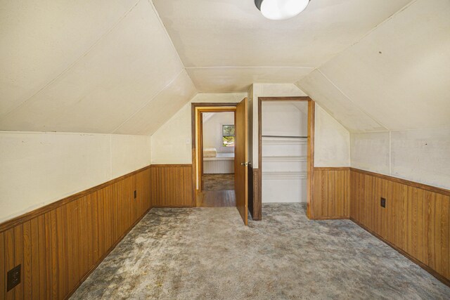 bonus room featuring lofted ceiling, wood walls, and light colored carpet