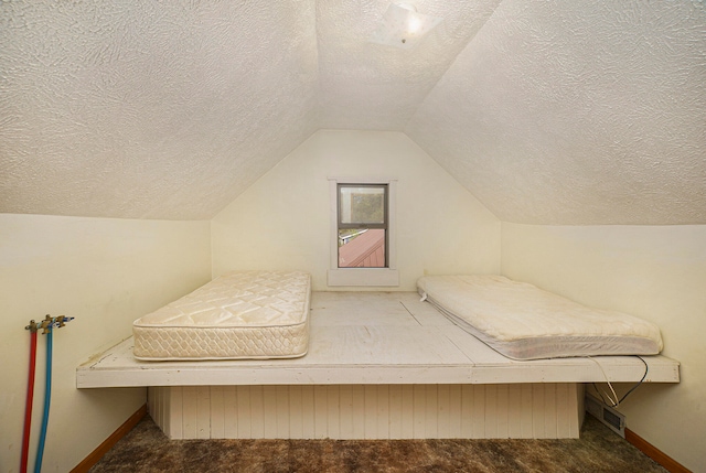 bedroom featuring lofted ceiling, a textured ceiling, and carpet floors