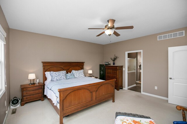 bedroom featuring ceiling fan, ensuite bath, and light carpet