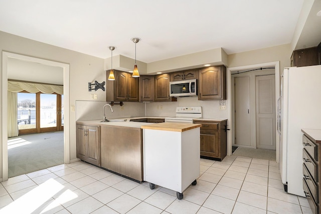 kitchen with range with electric cooktop, a sink, stainless steel microwave, freestanding refrigerator, and light tile patterned floors